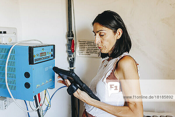 Mature woman using tablet PC by inverter at solar power station