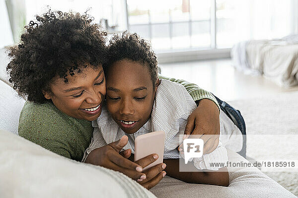 Happy mother with son using smart phone at home