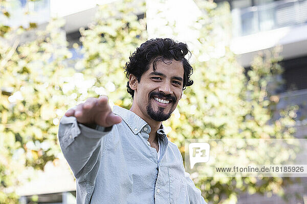 Happy man with goatee gesturing on sunny day