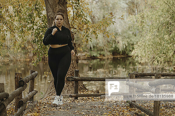 Determined young woman jogging in autumn park
