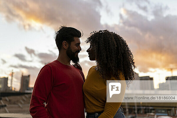 Happy young couple standing under sky at sunset