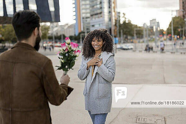 Young man giving bouquet of flowers to woman at footpath