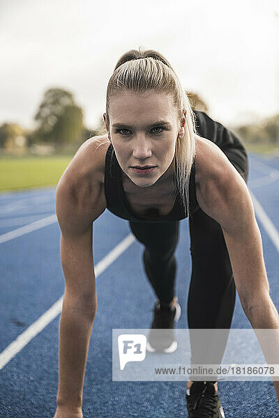 Confident athlete at starting line of running track