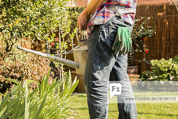 Close-up of man holding watering can in garden
