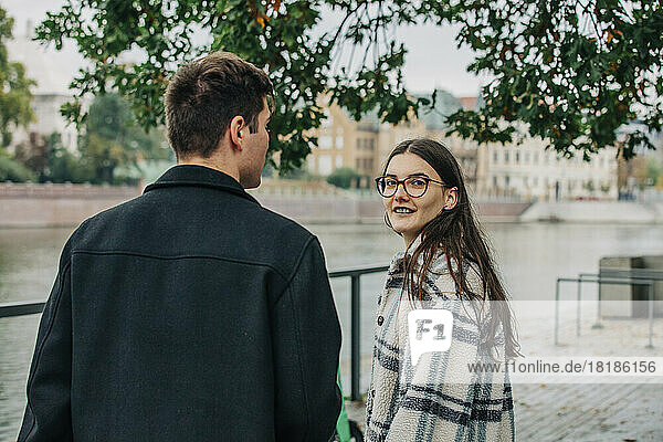 Young woman with eyeglasses standing by boyfriend on footpath