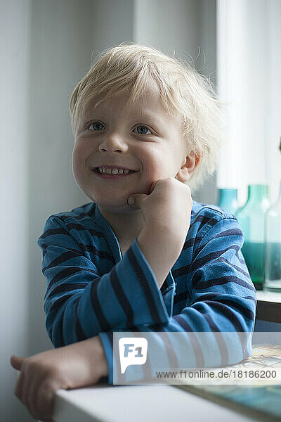 Portrait of smiling little boy with hand on his face