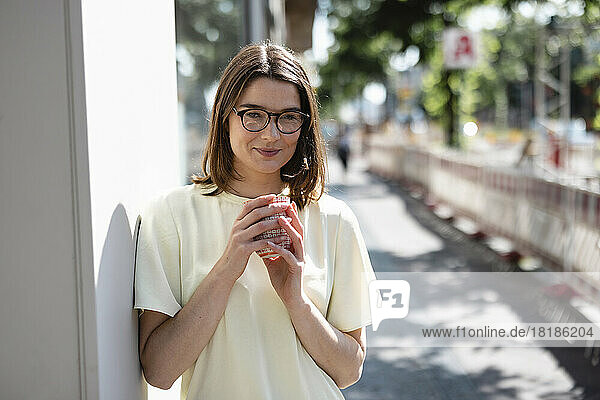 Smiling businesswoman holding coffee cup on footpath