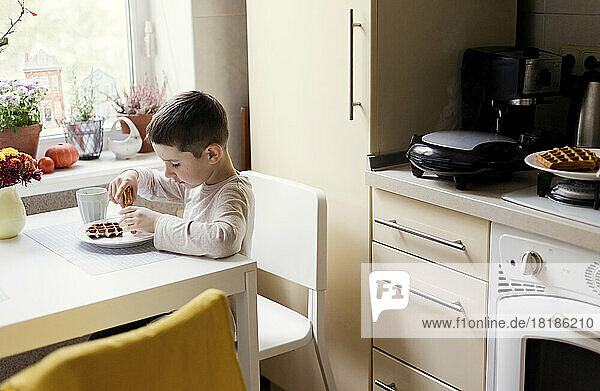 Boy having breakfast on dining table in kitchen