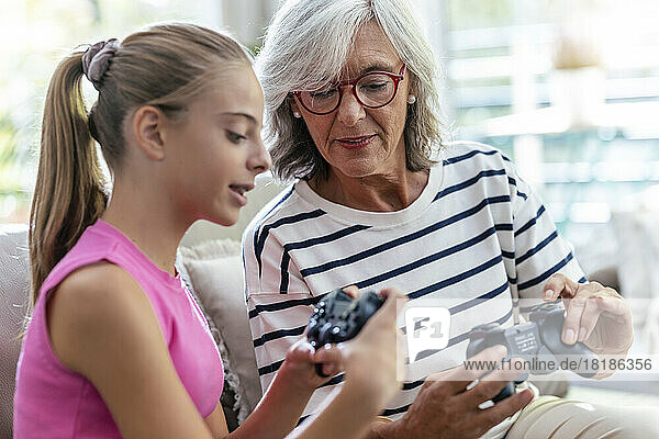 Granddaughter teaching grandmother to use joystick for playing video game at home