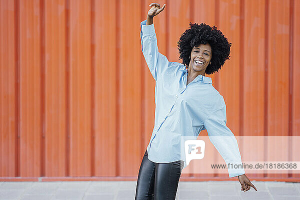 Junge Frau hat Spaß beim Tanzen vor orangefarbener Wand