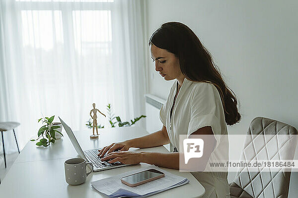 Businesswoman using laptop on table at home office