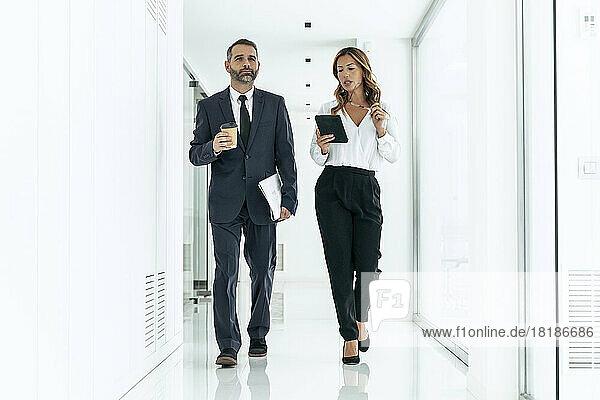 Business colleagues walking in office corridor