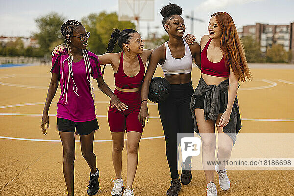 Fröhliche junge Freunde  die gemeinsam auf dem Basketballplatz spazieren gehen