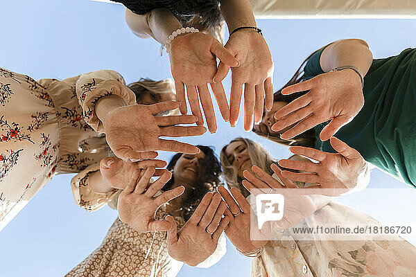 Friends showing palms standing under blue sky