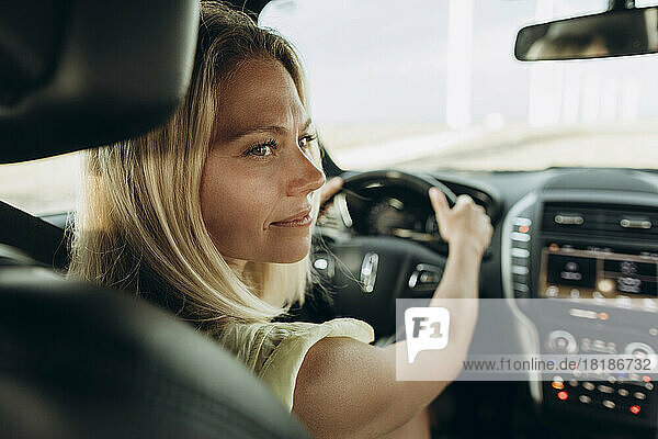 Thoughtful woman holding steering wheel sitting in car