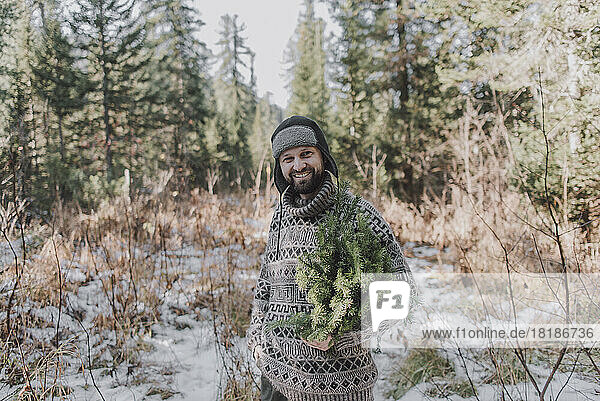 Smiling mature man wearing warm clothing in forest