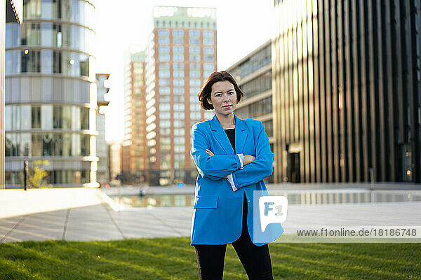 Confident businesswoman standing with arms crossed in front of building