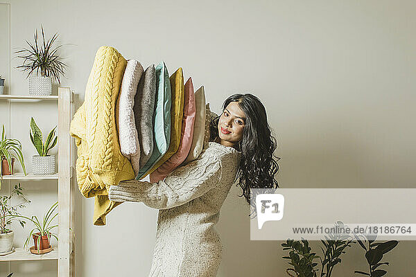 Smiling woman holding pillows and blankets at home