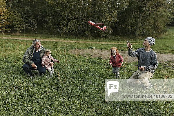 Family enjoying together playing with model airplane on grass