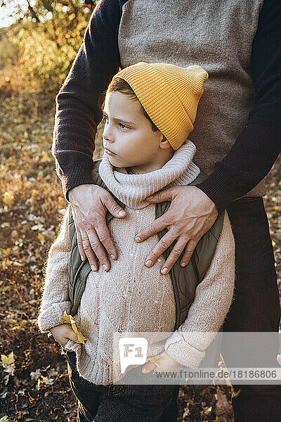 Boy wearing knit hat standing with father