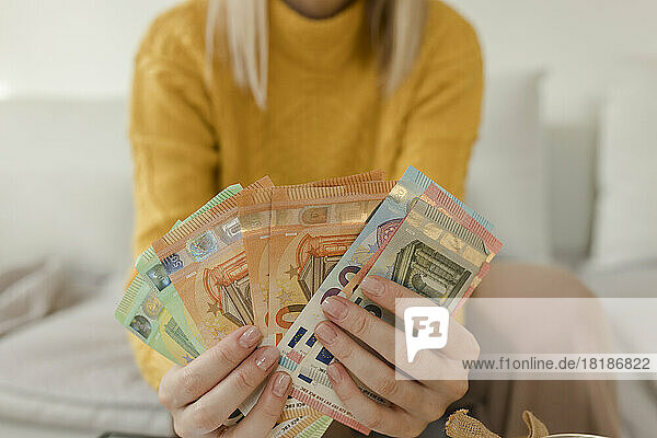 Frau zählt Geld im heimischen Wohnzimmer