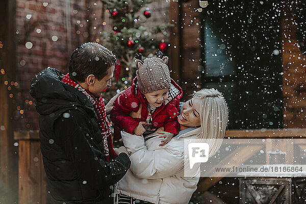Cheerful father and mother playing with son in snow