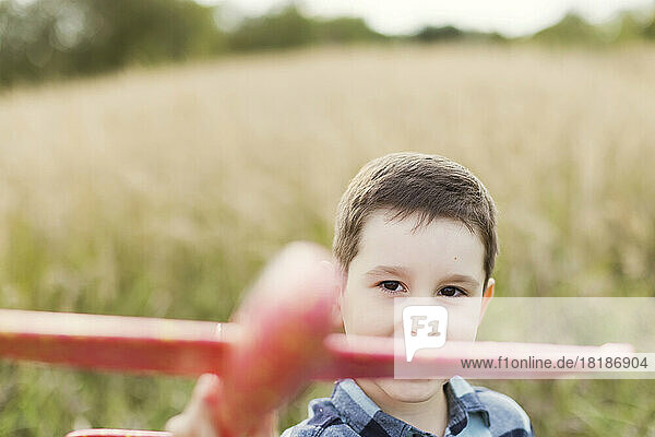 Cute boy playing with toy airplane in field
