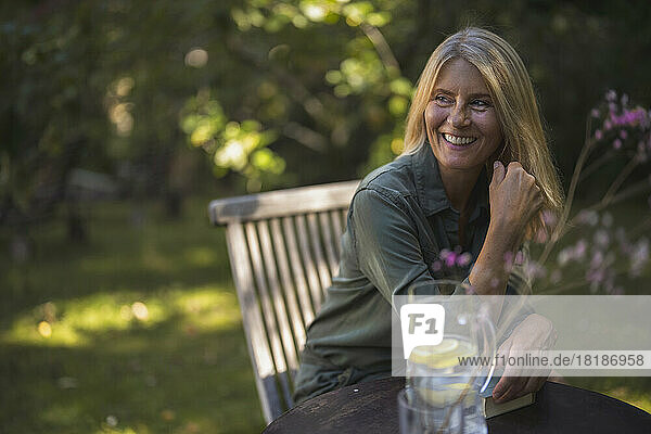 Happy mature woman with blond hair sitting in garden