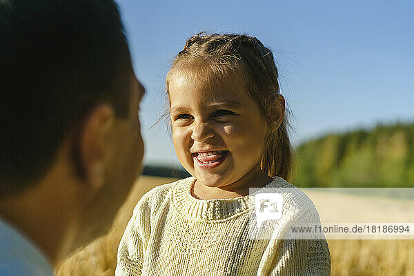 Glückliches süßes Mädchen mit Vater auf dem Feld an einem sonnigen Tag