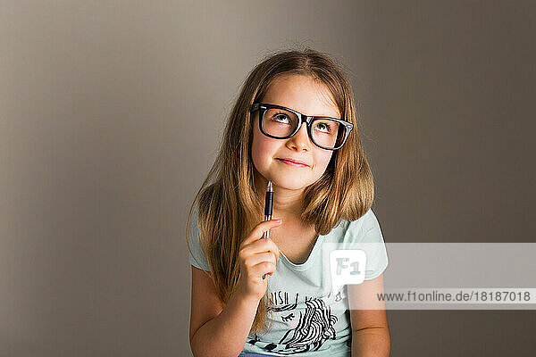 Portrait of smart girl with oversized glasses thinking