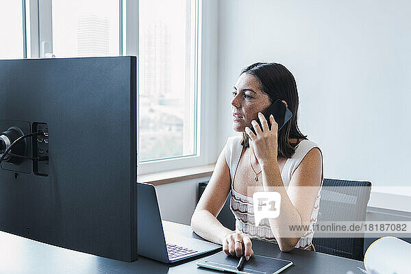Young businesswoman talking through smart phone in office