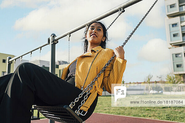Young woman enjoying on swing at playground