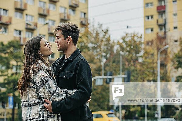 Smiling young couple embracing each other in city