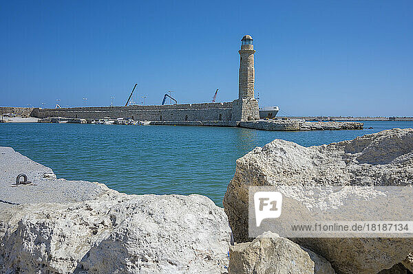 Greece  Crete  Rethymno  Lighthouse with coastal boulders in foreground