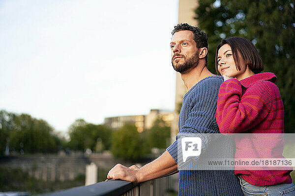 Romantic couple wearing warm clothing standing near railing