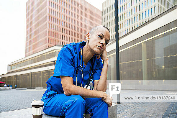 Thoughtful mature nurse sitting on bench