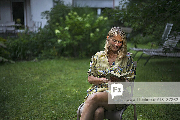 Smiling mature woman reading book in garden