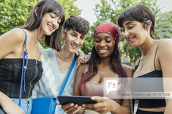 Smiling woman sharing mobile phone with friends