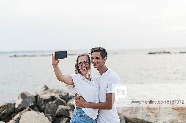 Glückliches Paar macht Selfie mit dem Handy am Strand