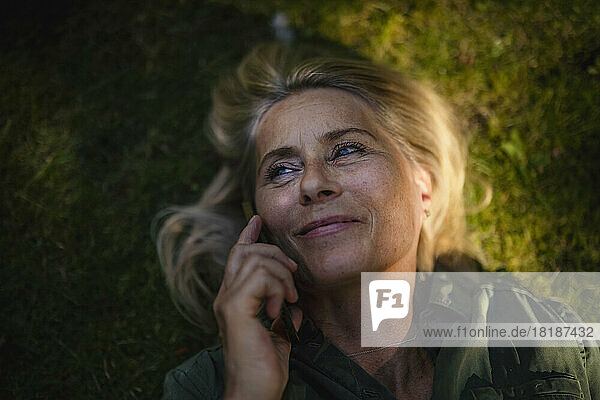 Smiling woman talking over mobile phone in garden