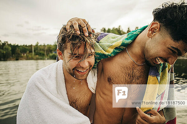 Happy male friends wearing towel enjoying during vacation