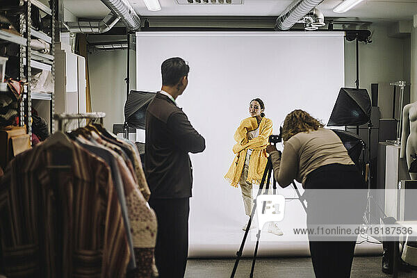 Weibliches Modemodell  das während eines Fotoshootings im Studio vor einem Hintergrund posiert
