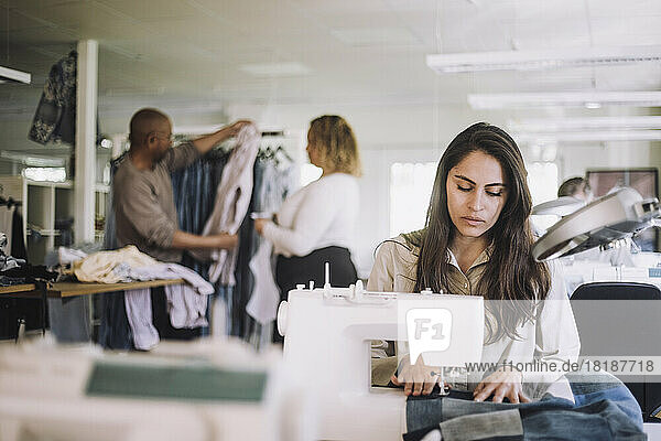 Female designer professional working on sewing machine at workshop