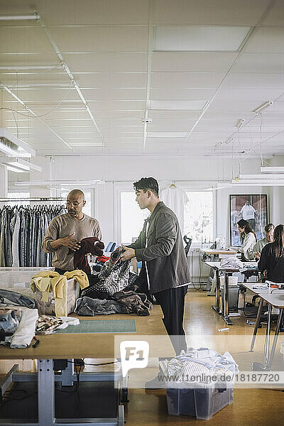 Male design professionals sorting recycled clothes at workshop