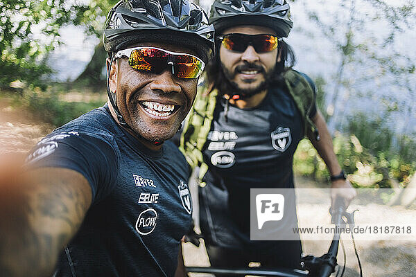 Happy male cyclist taking selfie with friend