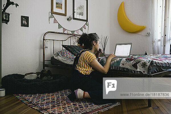 Seitenansicht einer Frau  die einen Laptop benutzt  während sie im Schlafzimmer zu Hause sitzt