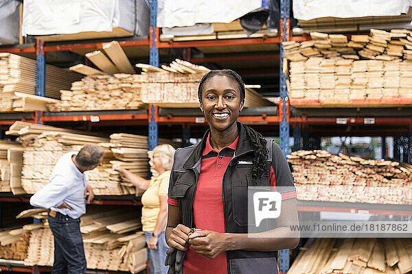 Porträt einer lächelnden Verkäuferin  die vor einem Regal in einem Baumarkt steht