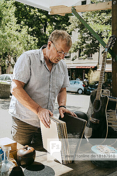 Älterer Mann wählt Schallplatten aus  die in der Nähe eines Flohmarktstandes stehen
