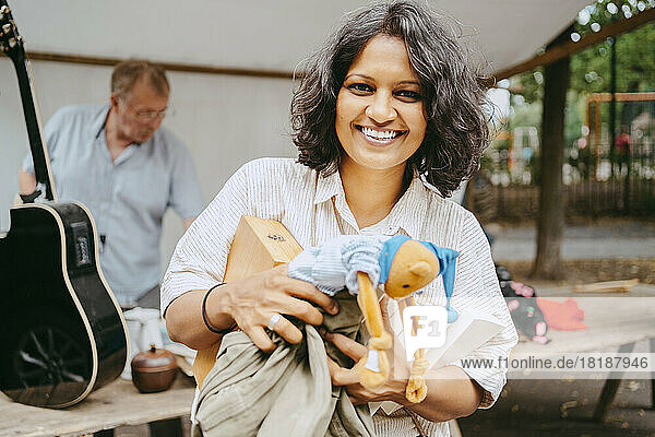 Porträt einer glücklichen Frau mit Büchern und Stofftier auf dem Flohmarkt