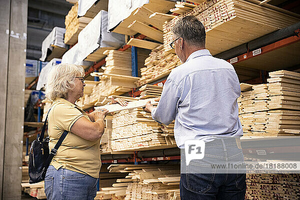 Male and female customers choosing plank at hardware store